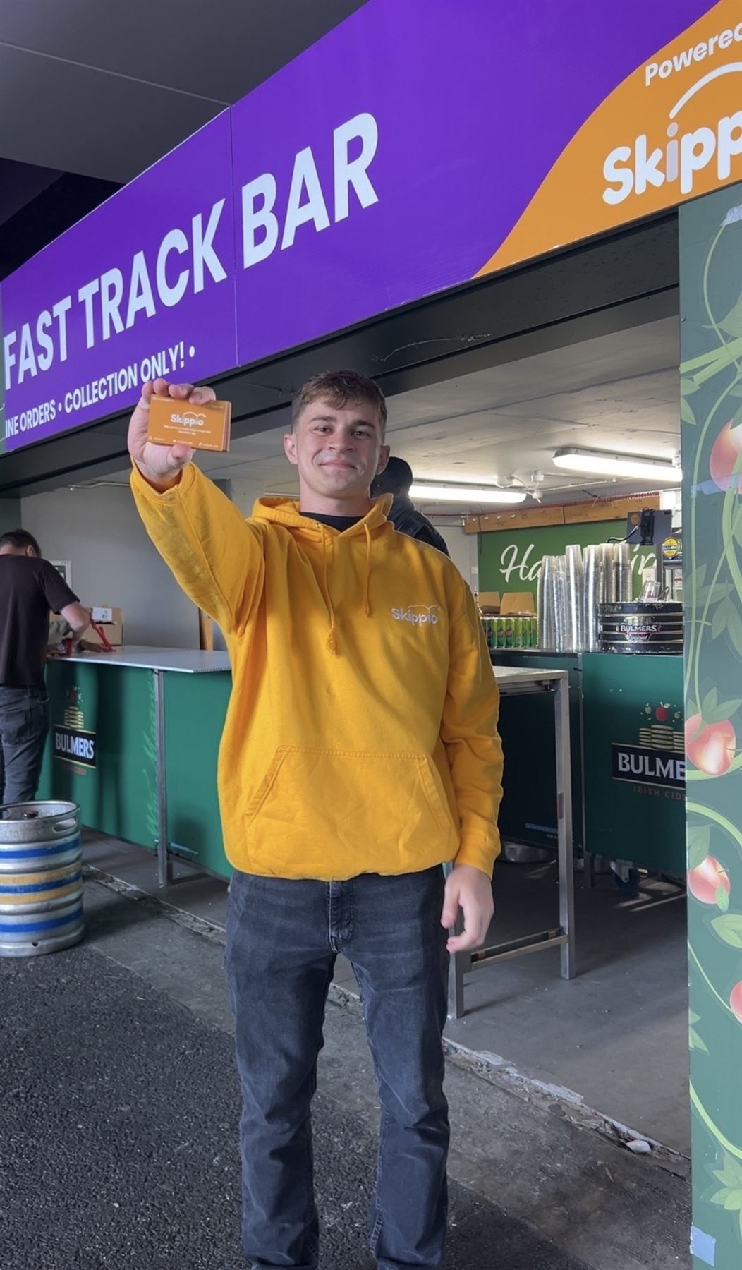 Skippio team member holding a Skippio card at a fast track bar for collection-only orders